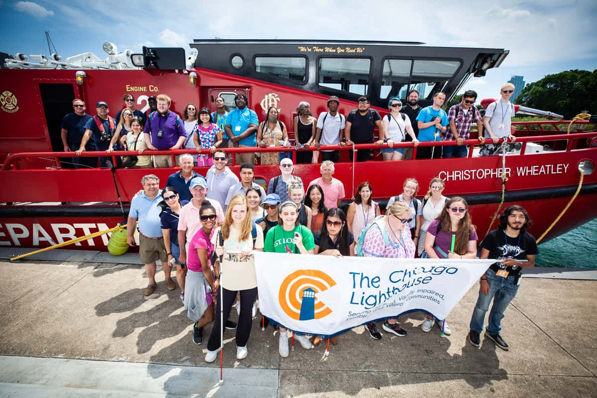 All of the SITC participants gathered in front of a red fire department boat