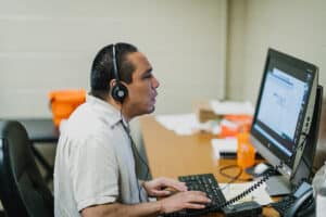 A visually impaired man with a headset uses a computer