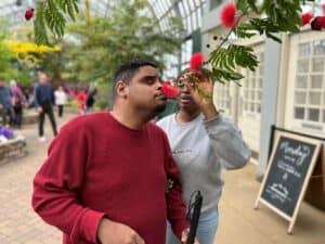 An Adult Living Skills participant smells a flower on a field trip to Garfield Park Conservatory