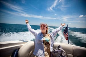 A teenager from our Youth Transition Program spreads her arms out at the back of a boat on Lake Michigan.