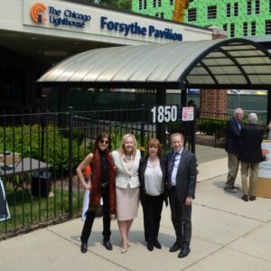 Julie Star, Janet Szlyk, Sandy Forsythe, and Thomas Deutsch stand in front of The Chicago Lighthouse Forsythe Pavilion.