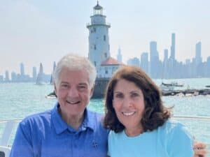 Nick and Nancy Berberian smile at the camera with The Chicago Lighthouse behind them on Lake Michigan