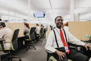 A young man who is blind works in a busy contact center