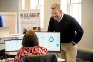 A supervisor smiles and assists a contact center agent at Blindsight Delaware Enterprises