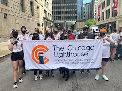 Members of The Chicago Lighthouse holding a banner and marching in the Disability pride parade