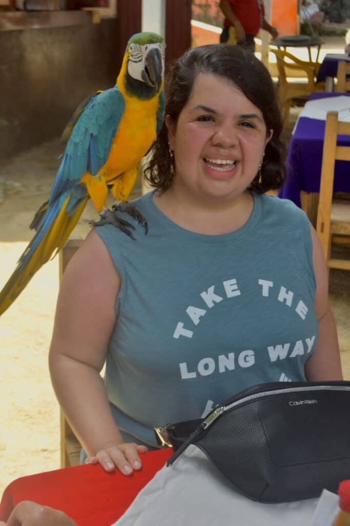 Sandy posing for a photo with a parrot on her shoulder