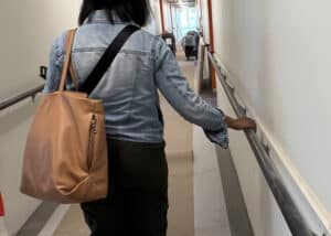 Someone walking down the hall of the Foglia building holding the railing