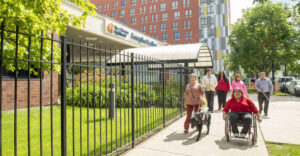 A group of individuals, some with disabilities, walk on the sidewalk near The Chicago Lighthouse