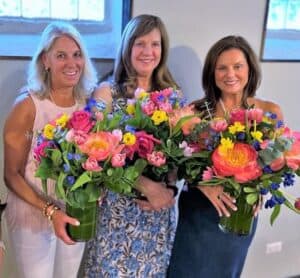 Trio of women holding 3 sets of flowers during the housewarming party