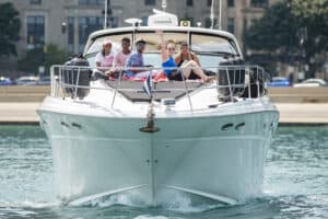 Five Youth Transition Program participants sitting at the front of a large yacht, smiling and waving at the camera.