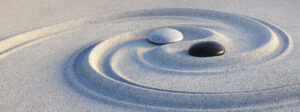 two stones perfectly positioned in a yin/yang pattern of sand