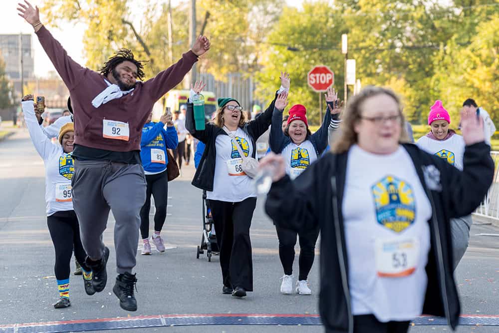 Employees of The Lighthouse Jump for joy as they cross the finish line