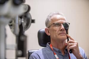 A man holds a cover over one eye as he reads a vision chart.