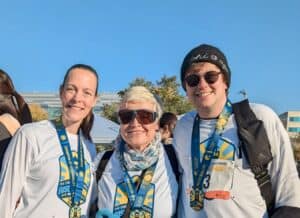 Pat stands with Patrick A. and Laura H. at the Rise to Shine Run & Walk. They all wear Rise to Shine shirts and finisher medals and smile.