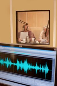 Two men talk in a recording booth