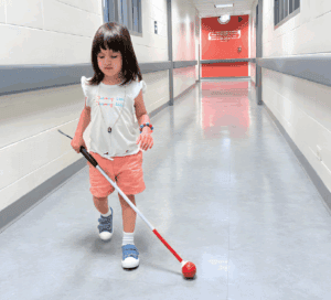 A young girl who is blind walks with a white cane at The Lighthouse