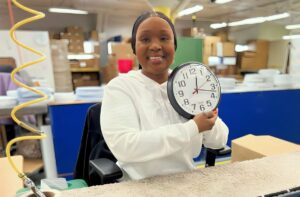 Shaneka Wade Lee holding up a clock in the clock factory.