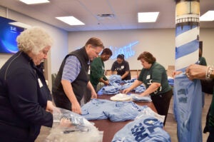 A group of Northern Trust employees pack Rise to shine bags with shirts