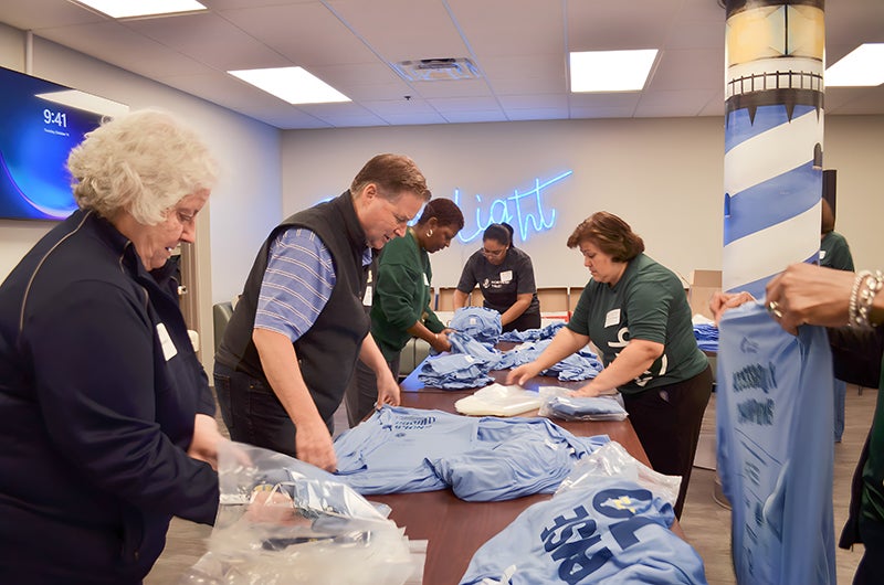 A group of Northern Trust employees pack Rise to shine bags with shirts