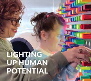 A girl who is visually impaired plays with a giant light-bright board with her teacher
