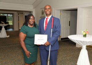 Quan stands with his wife, holding his certificate proudly at the award ceremony.