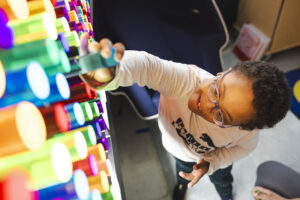A child who is disabled places a peg in a life-sized light bright board